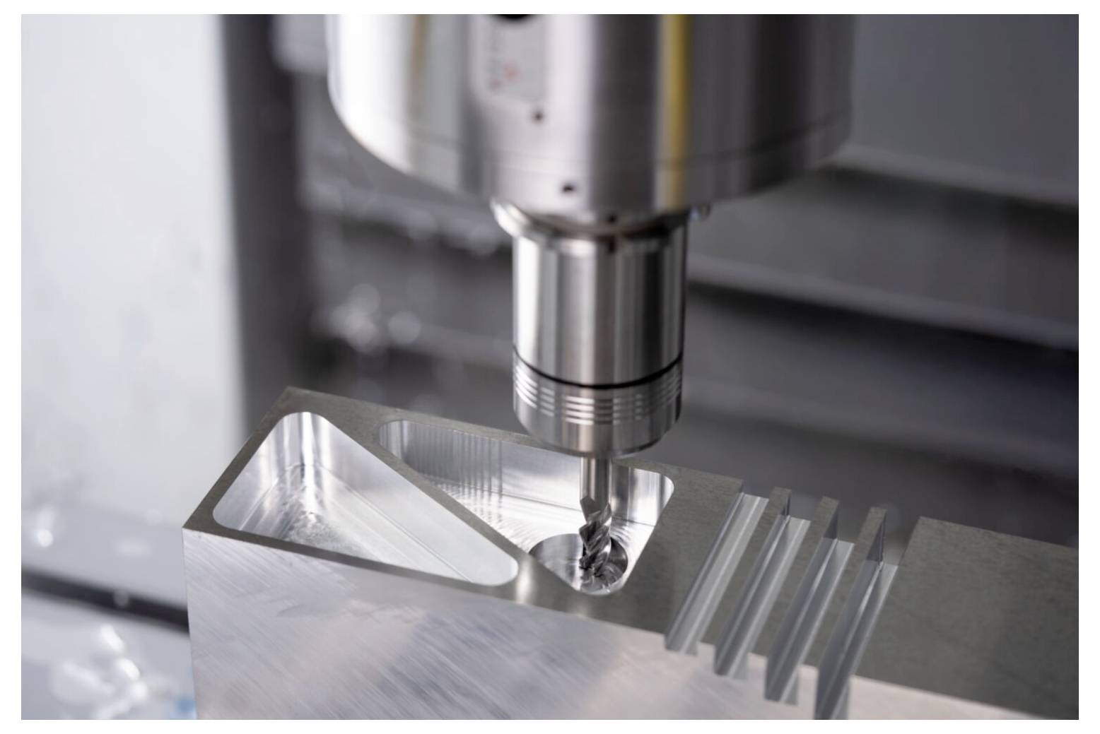 Maszyna CNC dokładnie wiercąca blok metalowy, prezentująca proces obróbki w środowisku przemysłowym.