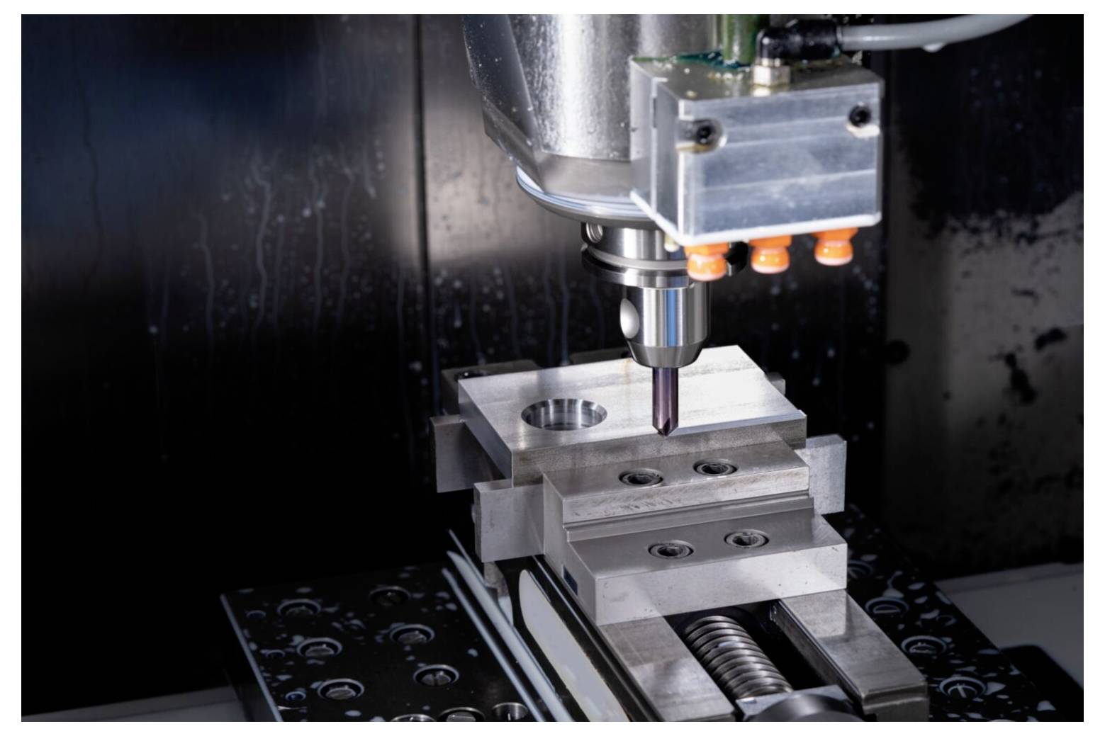 Frezarka CNC precyzyjnie obrabiająca blok metalowy, prezentująca zaawansowaną technologię obróbki stosowaną w przemyśle produkcyjnym.