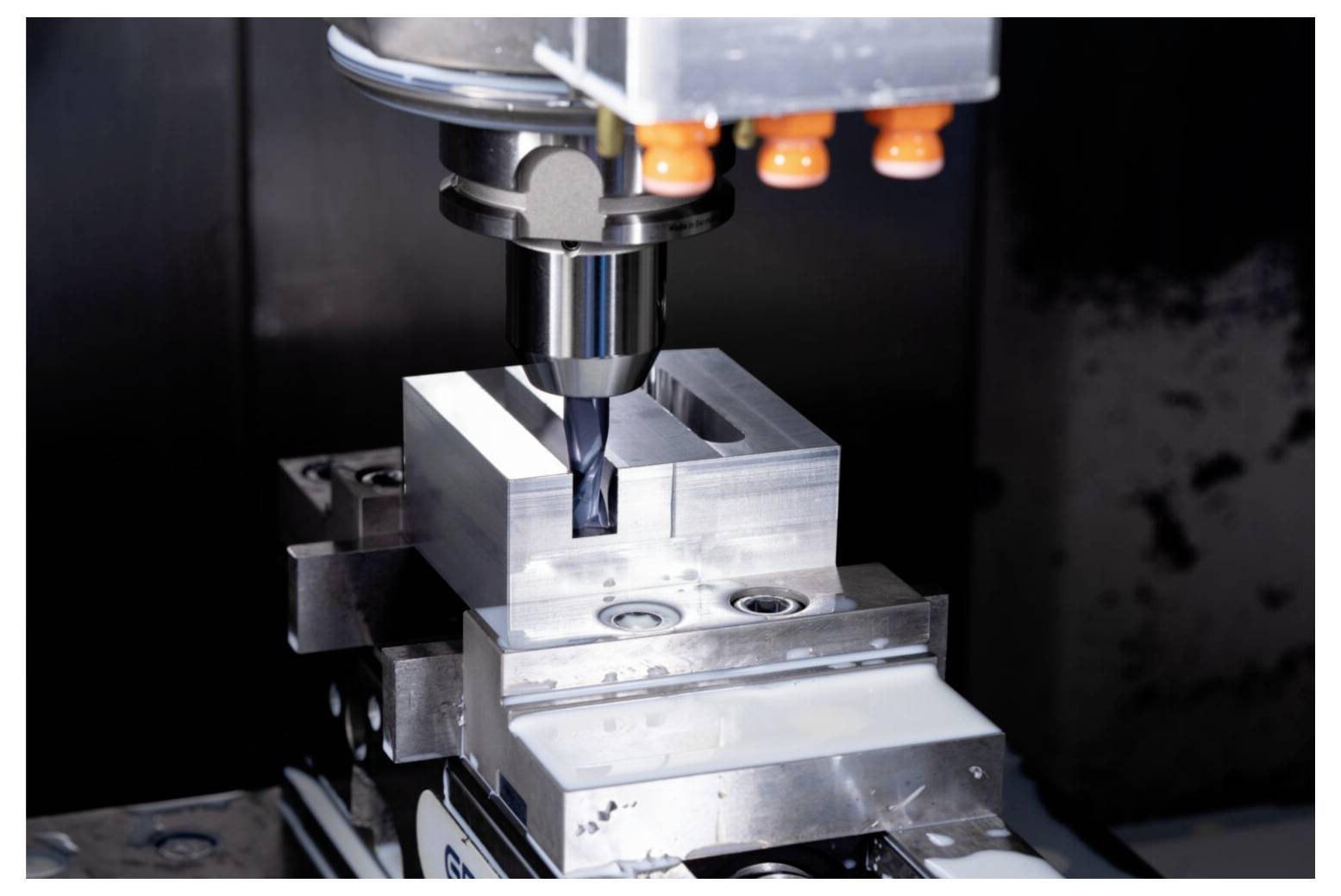 Maszyna CNC aktywnie nacina blok metalowy, kształtując go z precyzją. Scena podkreśla zaawansowaną technologię produkcyjną.