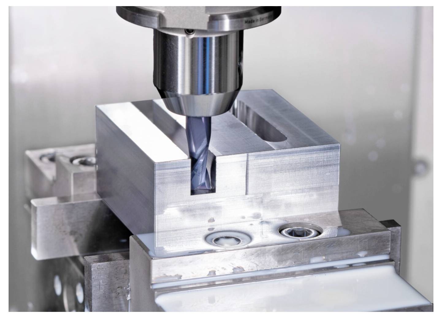 Metalowy blok poddawany frezowaniu za pomocą obrabiarki CNC, wycinającej prostokątny kształt, podkreślający precyzyjną obróbkę w procesie produkcyjnym.