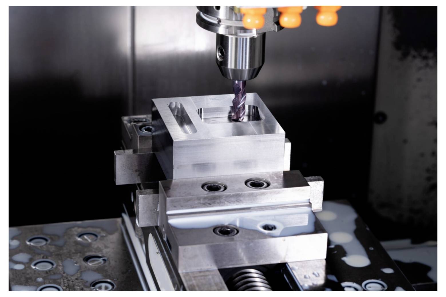 Maszyna CNC precyzyjnie frezująca prostokątny blok metalowy, prezentująca przykład zautomatyzowanej technologii obróbki metalu.