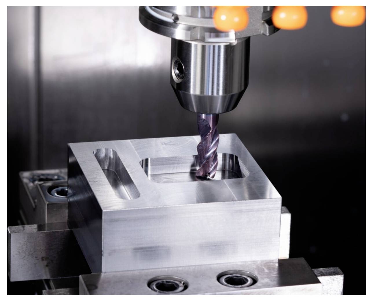 Metalowy blok precyzyjnie obrabiany na frezarce CNC, prezentujący zaawansowaną technologię produkcyjną i precyzję narzędzi.