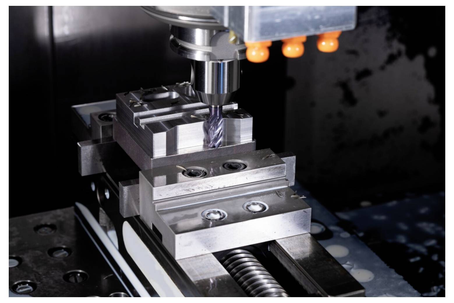 Zbliżenie frezarki CNC obrabiającej z precyzją element metalowy w warunkach warsztatowych, podkreślające zaawansowaną technologię przemysłową.