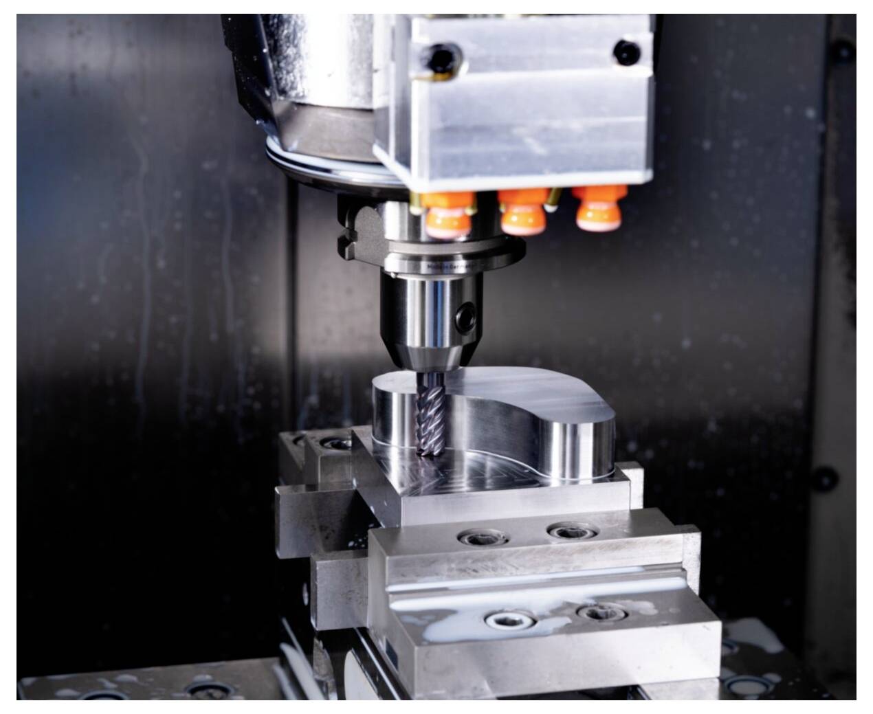 Maszyna CNC pracuje, precyzyjnie obrabiając metalowy element, prezentując skomplikowane frezowanie zbliżające się do ukończenia w przemysłowym otoczeniu.
