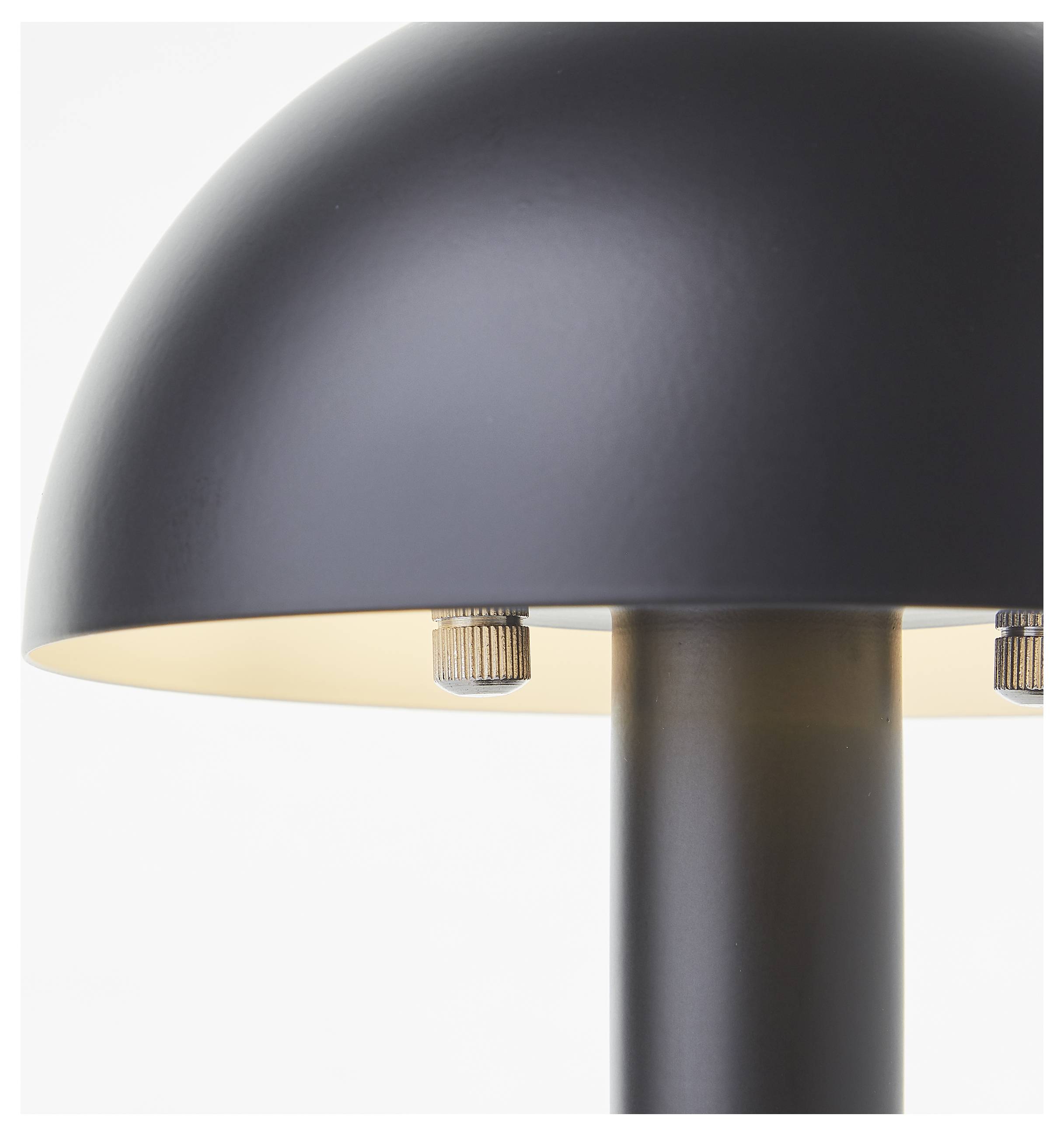 Zbliżony widok nowoczesnej, czarnej lampy stołowej w kształcie kopuły z metalowymi mocowaniami, podkreślającej jej minimalistyczny design.