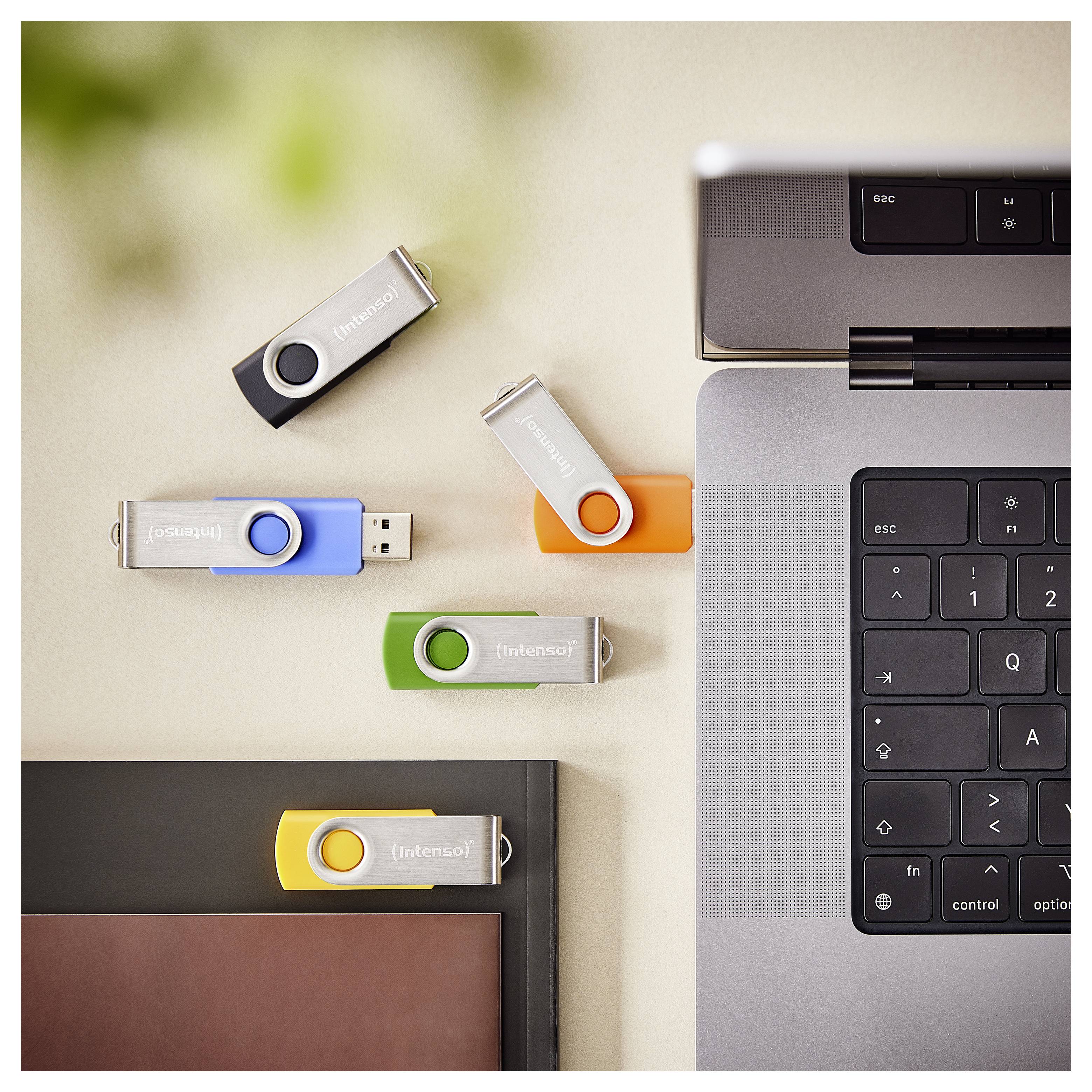 Laptop na biurku z pięcioma dyskami USB w różnych kolorach, wskazujący na opcje transferu danych lub przechowywania.
