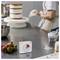 Osoba dekoruje tort na obracającym się talerzu kuchennym, z truskawkami na blacie i minutnikiem pokazującym pozostałe 10 minut.