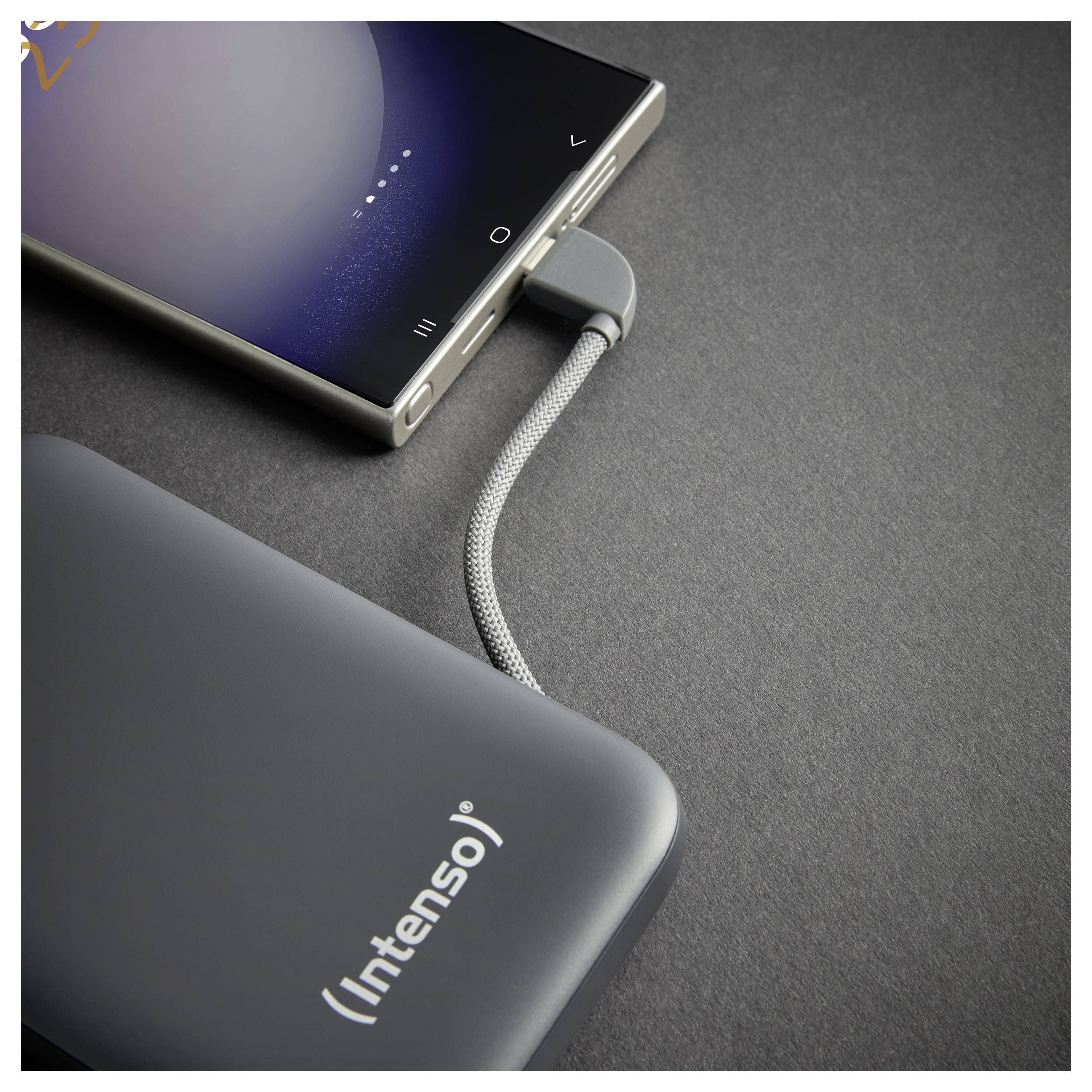 Smartfon podłączony do szarego powerbanku Intenso za pomocą plecionego kabla na ciemnej powierzchni, wskazujący na ładowanie lub transfer danych.