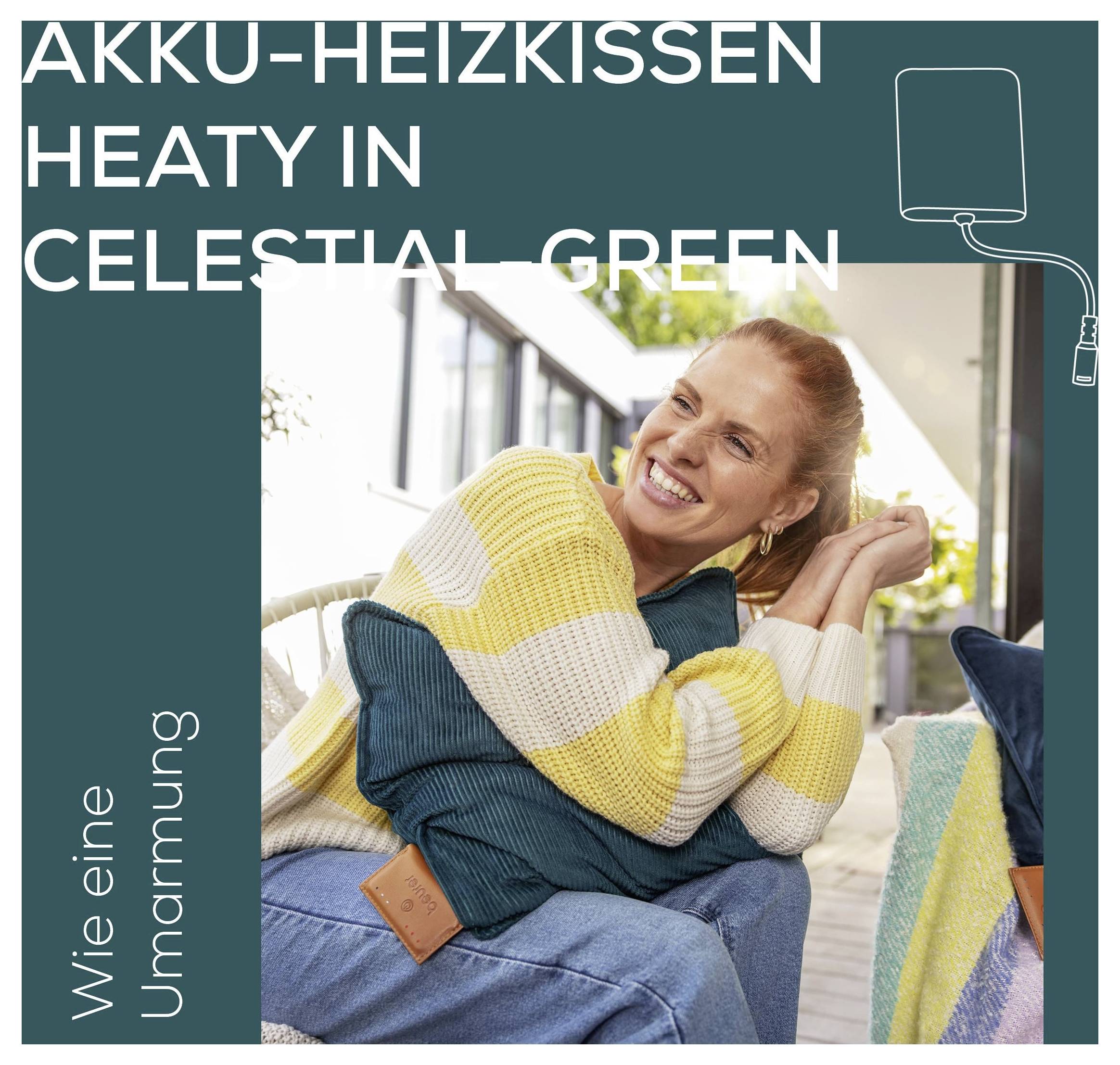 Kobieta siedzi w wygodnym fotelu, przytulając poduszkę. Tekst brzmi: Poduszka grzewcza Akku-Heizkissen Heaty w kolorze Celestial Green, Jak uścisk.