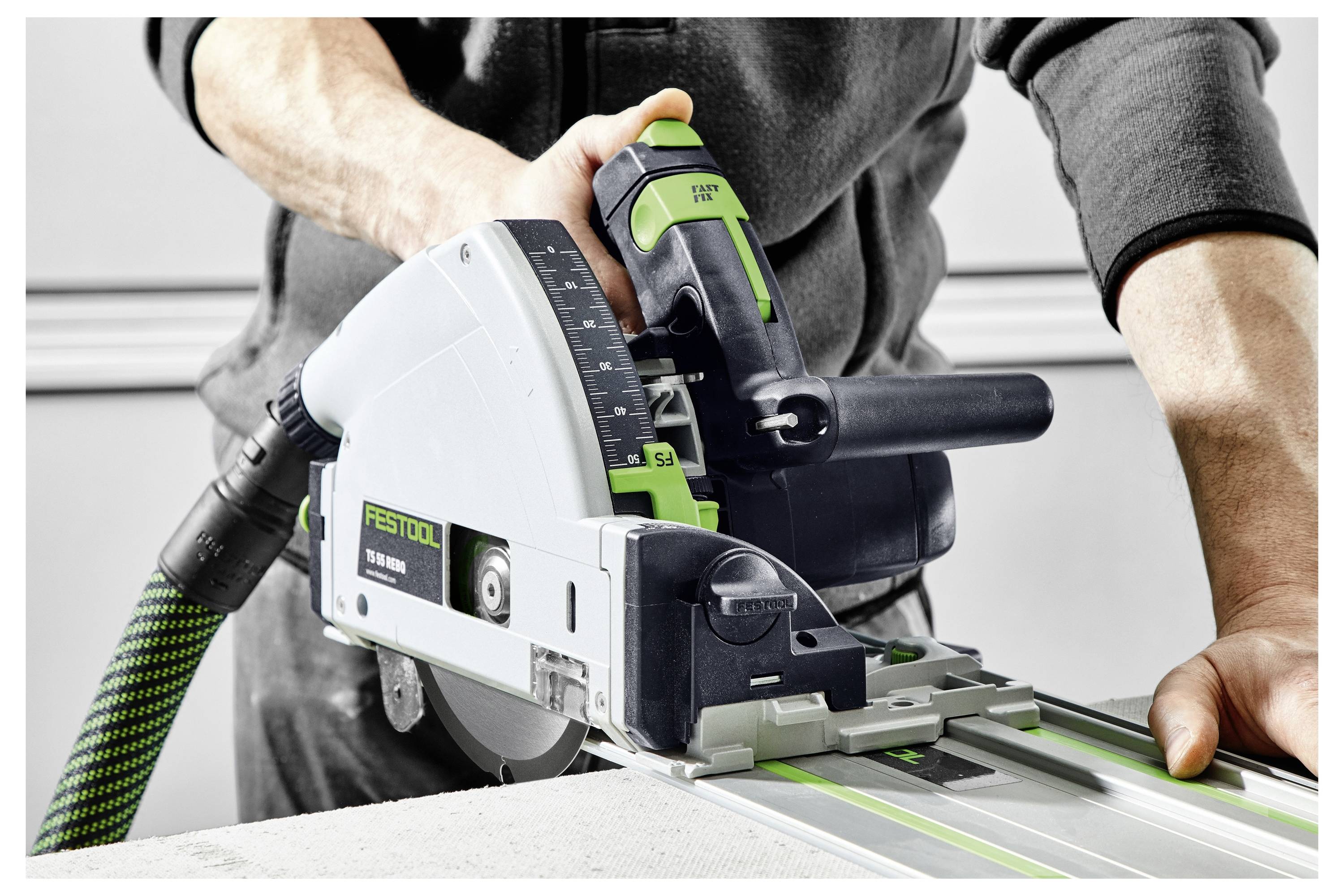 Osoba obsługująca piłę ścieżkową Festool, przecinająca kawałek materiału, demonstrujące precyzję i kontrolę za pomocą narzędzia.