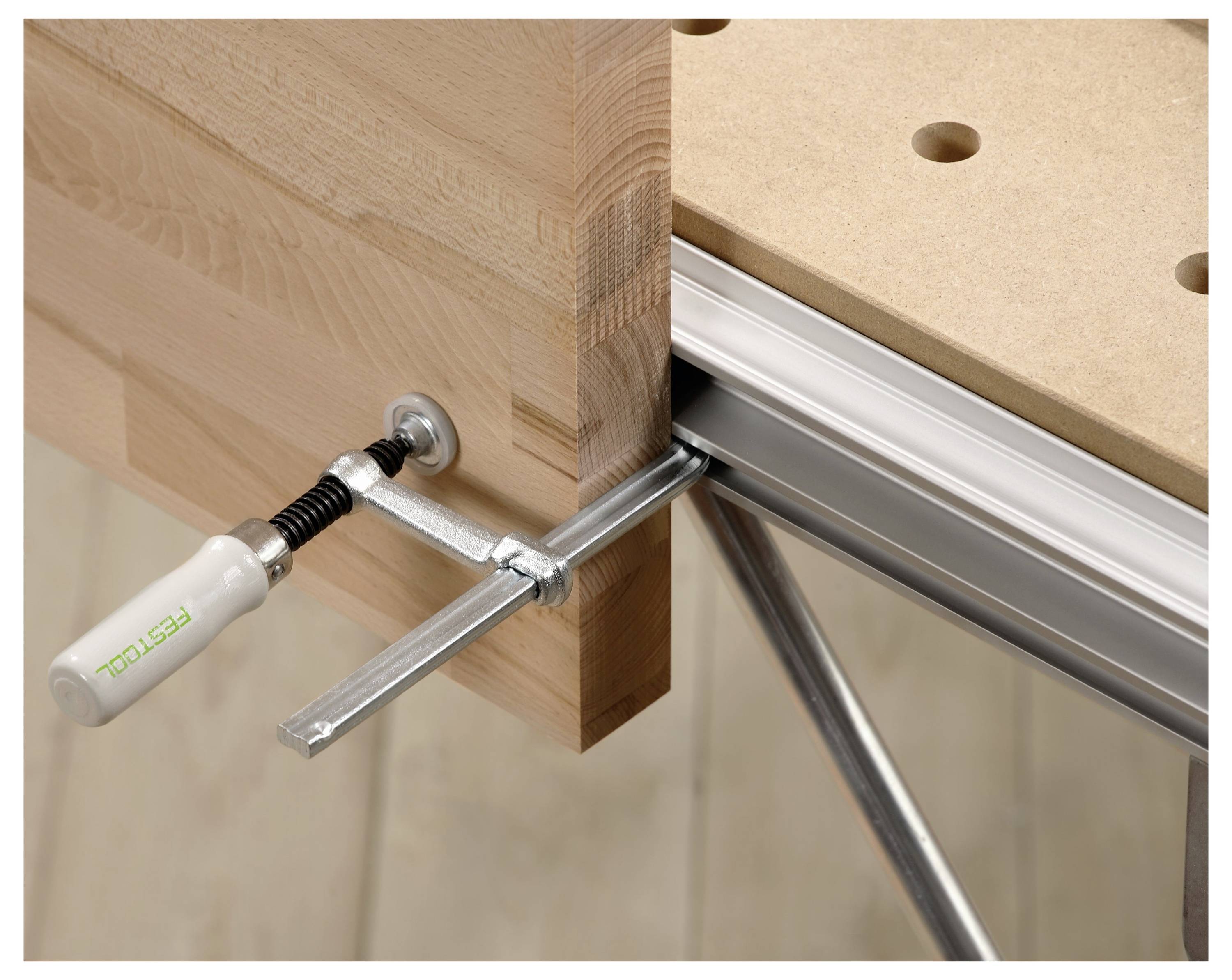 Drewniana deska zabezpieczona na warsztacie z użyciem imadła, ilustrująca drewnianą konfigurację warsztatową.