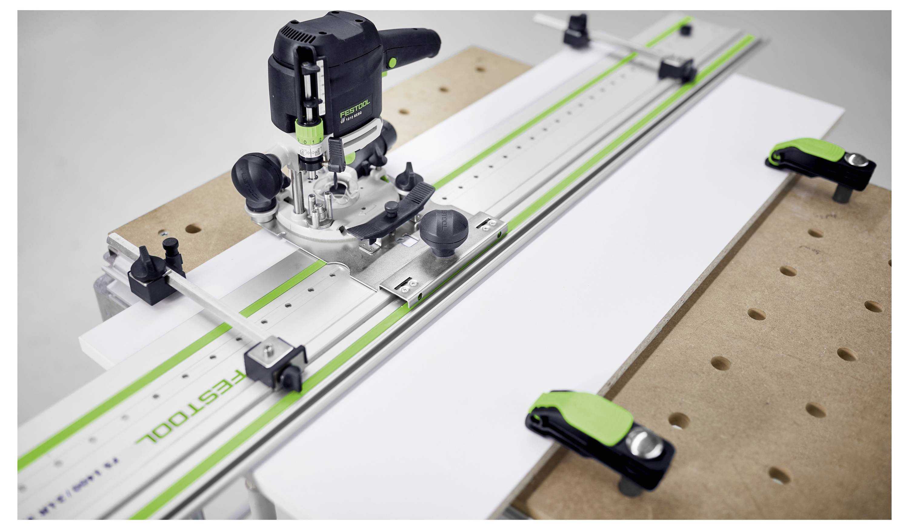 System routera na stole roboczym, wyposażony w szynę prowadzącą i zacieśniacze, używany do precyzyjnego cięcia i obróbki drewna.