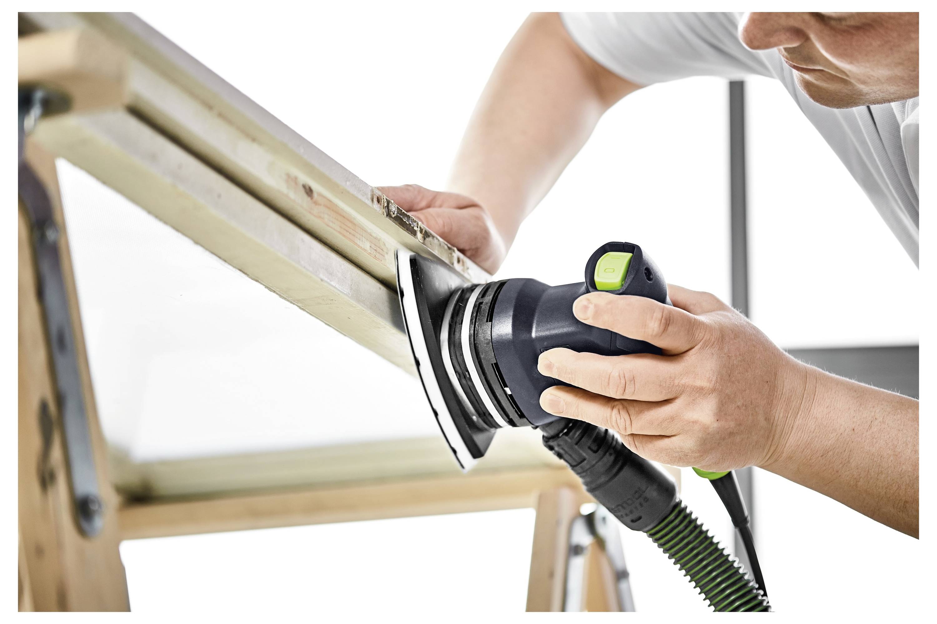 Torba narzędziowa z wieloma kieszeniami przechowuje różne ręczne narzędzia, w tym obcęgi i śrubokręty, położona na drewnianym stole roboczym w warsztacie.