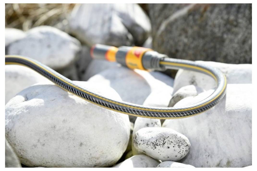 Elastyczna wąż leżąca na gładkich szarych kamieniach na zewnątrz, podkreślająca jej wytrzymałość i możliwość adaptacji w naturalnym otoczeniu.