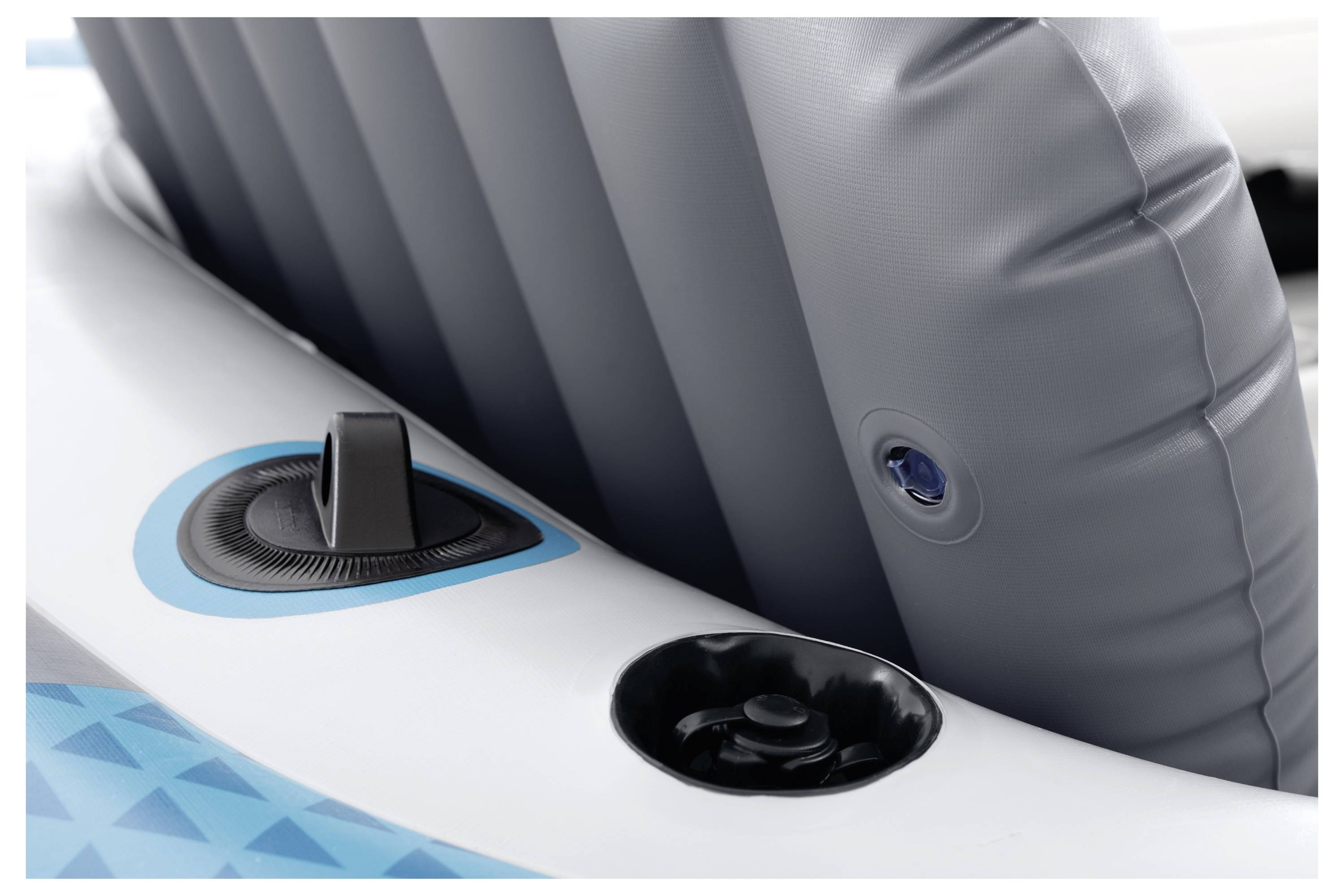 Zbliżenie szarego i niebieskiego siedziska do kajaka pneumatycznego z zaworkiem do napompowania powietrzem, gotowym do użytku na świeżym powietrzu.