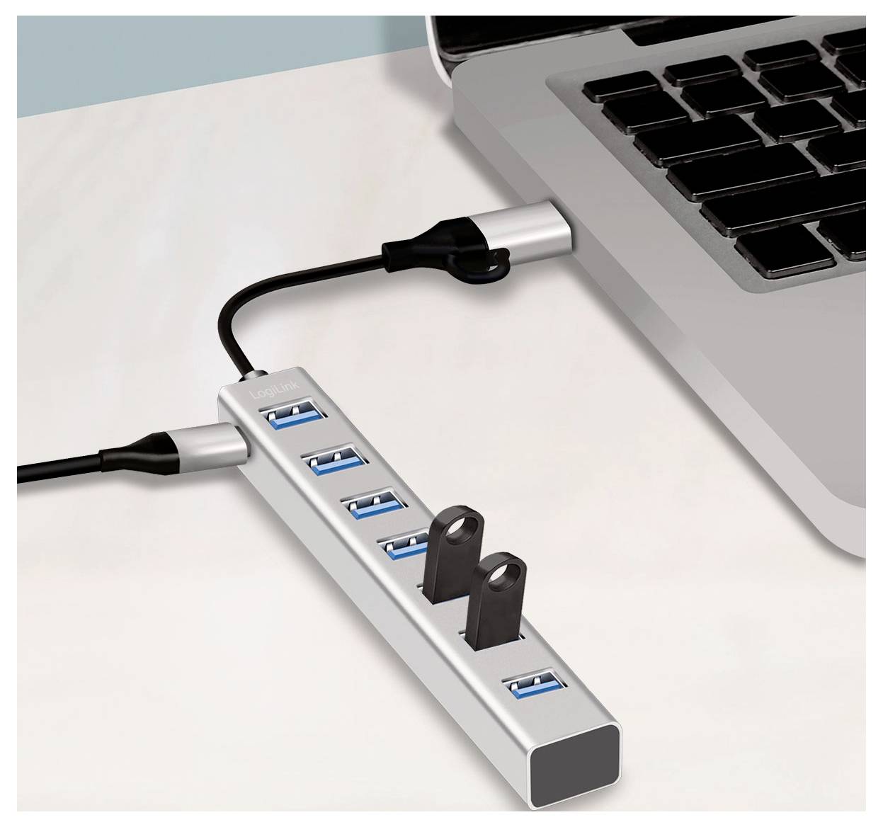 Concentrator USB podłączony do laptopa, z wieloma portami i jednym widocznym pustym gniazdem na biurku.