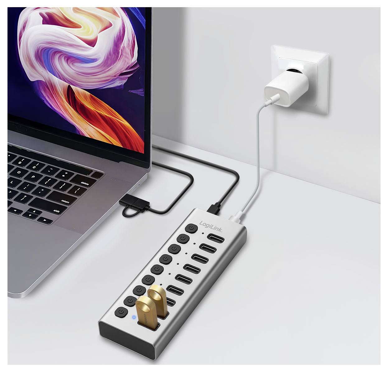 Laptop podłączony do wieloportowego hubu ładującego podłączonego do gniazda ściennego z kilkoma urządzeniami USB i wtyczkami sieciowymi.