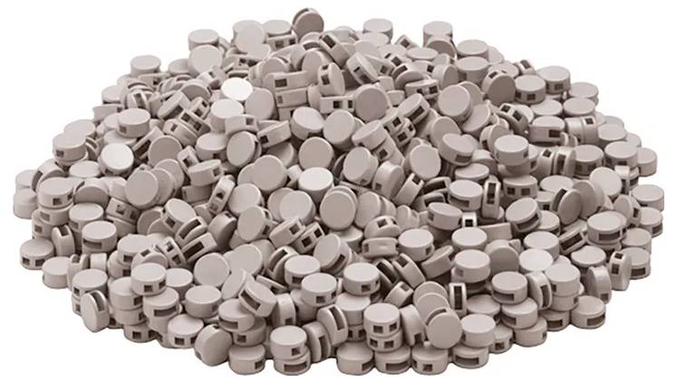 Duża kupa okrągłych, brązowych tabletek z rowkiem pośrodku, używanych do napojów musujących.