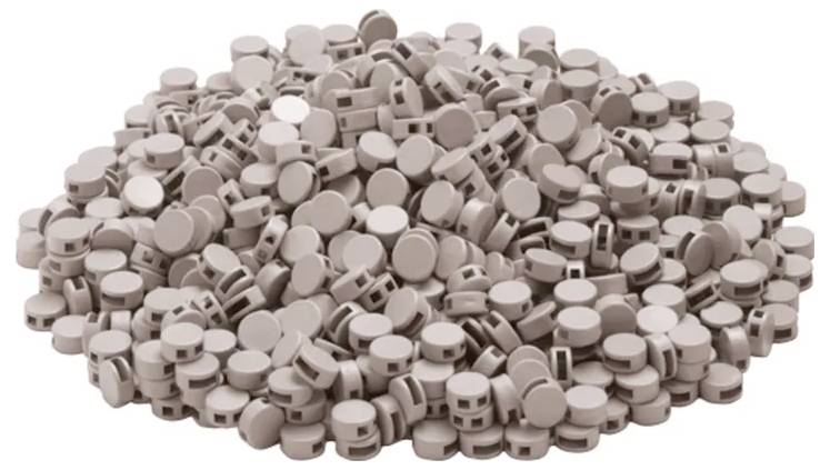 Duża sterta brązowych cylindrycznych tabletek z rowkami ułożona razem.