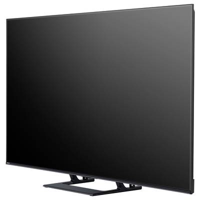 Telewizor z płaskim ekranem na statywie z minimalistyczną czarną ramką i refleksyjnym ekranem, widziany z perspektywy ukośnej.