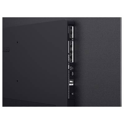 Tył montowanego na ścianie telewizora OLED z portami HDMI, USB i zasilania na bocznym panelu na tle fakturowanej ciemnej ściany.