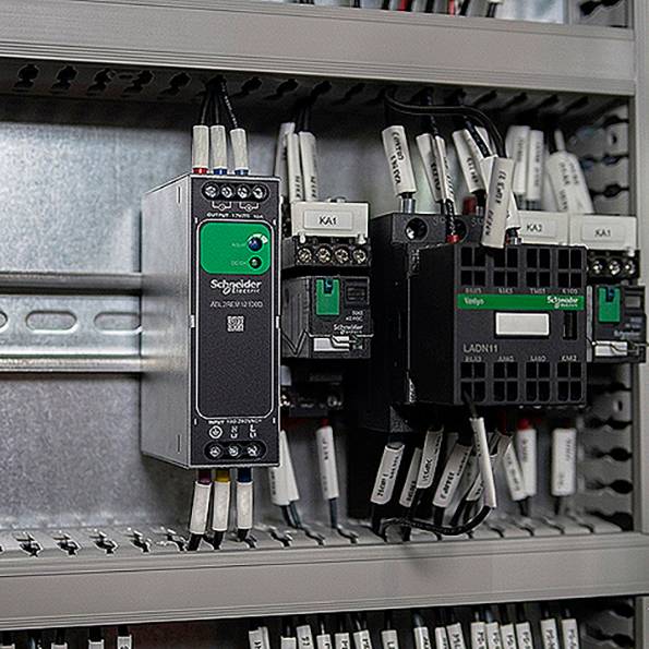 Szafa sterownicza z wieloma urządzeniami sterującymi Schneider Electric i podłączonymi przekaźnikami/stycznikami na szynie DIN.