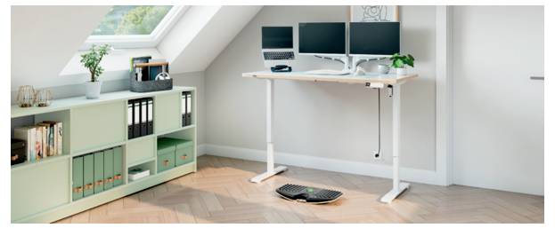 Jasny home office ze stanowiskiem do pracy na stojąco, trzema monitorami, klawiaturą i myszką, obok szafki do przechowywania w kolorze miętowej zieleni pod oknem dachowym.