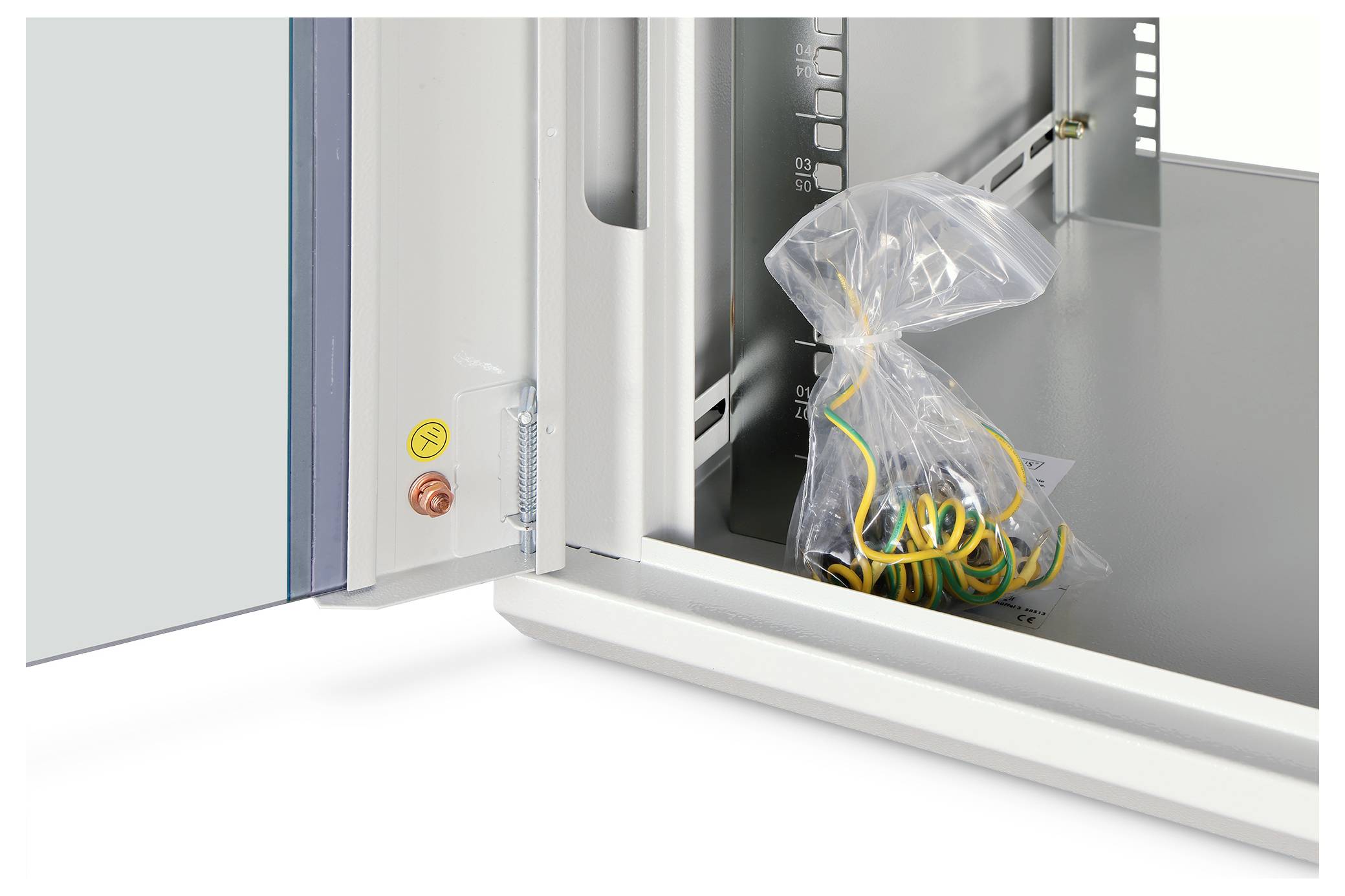 Otwarta szafka elektryczna z plastikową torbą żółto-zielonych przewodów w środku, obok zamontowanego wyłącznika zasilania i czerwono-żółtych przycisków sterowania.