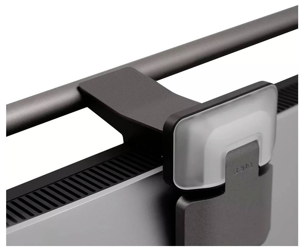 Zbliżenie na zacisk górny monitora i uchwyt kamery internetowej przymocowany do krawędzi ekranu.