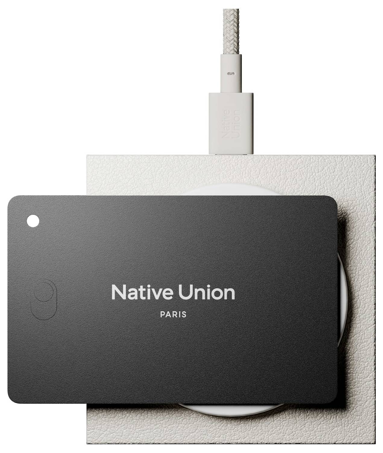 Zbliżenie na urządzenie ładujące Native Union i pleciony kabel na teksturowanej beżowej podstawie, pokazane w minimalistycznym ujęciu produktu.