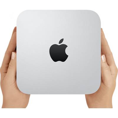Ręce trzymające srebrny Apple Mac mini z czarnym logo Apple wyśrodkowanym na przedniej stronie.