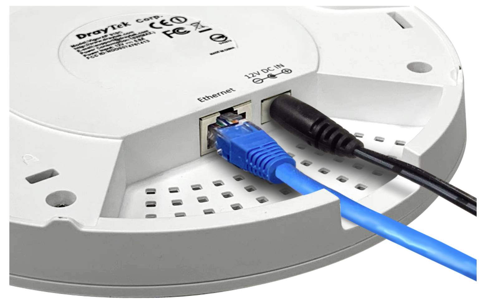 Zbliżenie urządzenia dostępowego D-Link montowanego na suficie z podłączonym kablem Ethernet i wtyczką zasilacza.