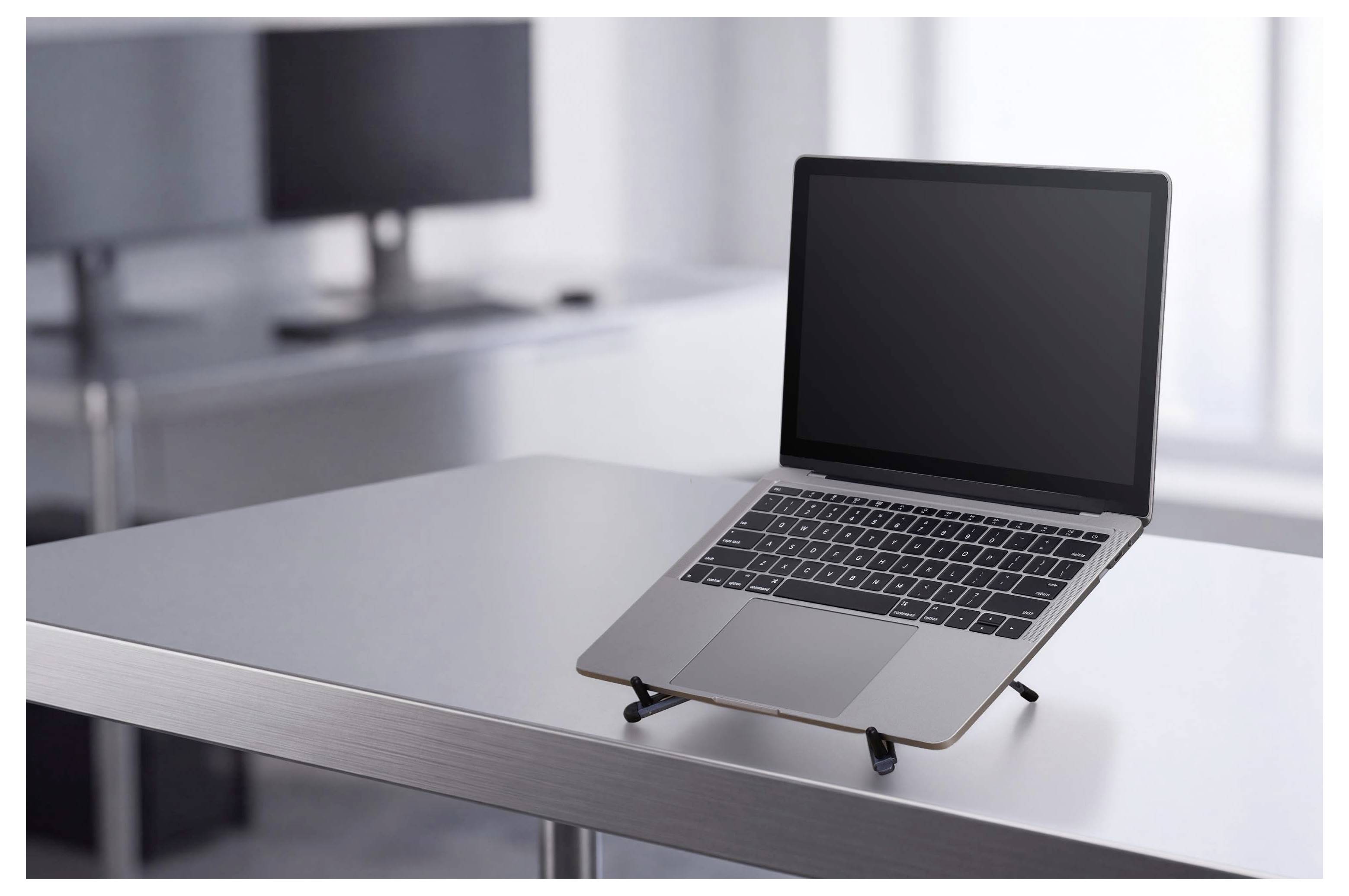 Otwarty laptop na eleganckim biurku w biurze z pustym ekranem i rozmytym przestrzenią roboczą w tle.