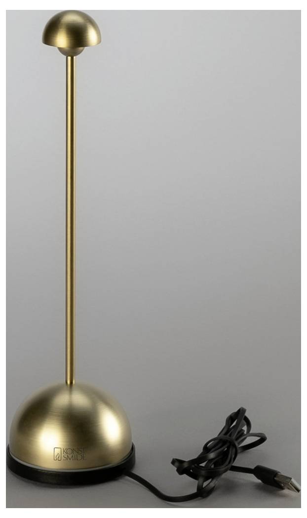 Lampa stołowa ze złotem wykończeniem z kopułowatą podstawą i abażurem, pokazana z podłączonym czarnym przewodem zasilającym na jednolitym szarym tle.