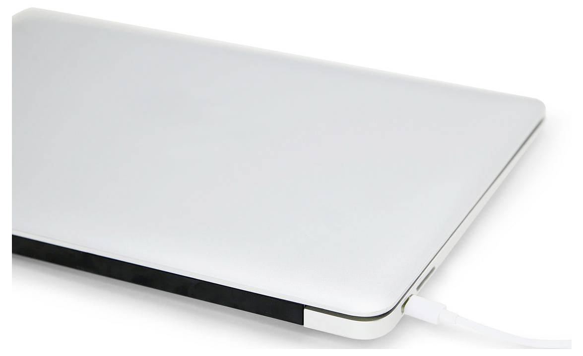 Zamknięty srebrny laptop podłączony do kabla ładowania na białym tle.