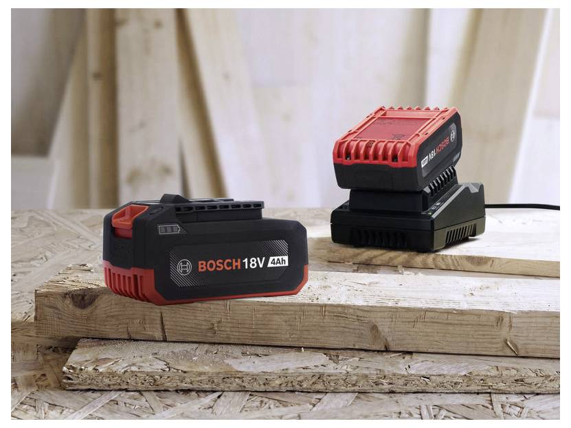 Pakiet baterii Bosch 18V 4Ah na pierwszym planie, wraz z ładowarką baterii Bosch i inną baterią na drewnianym stole roboczym.