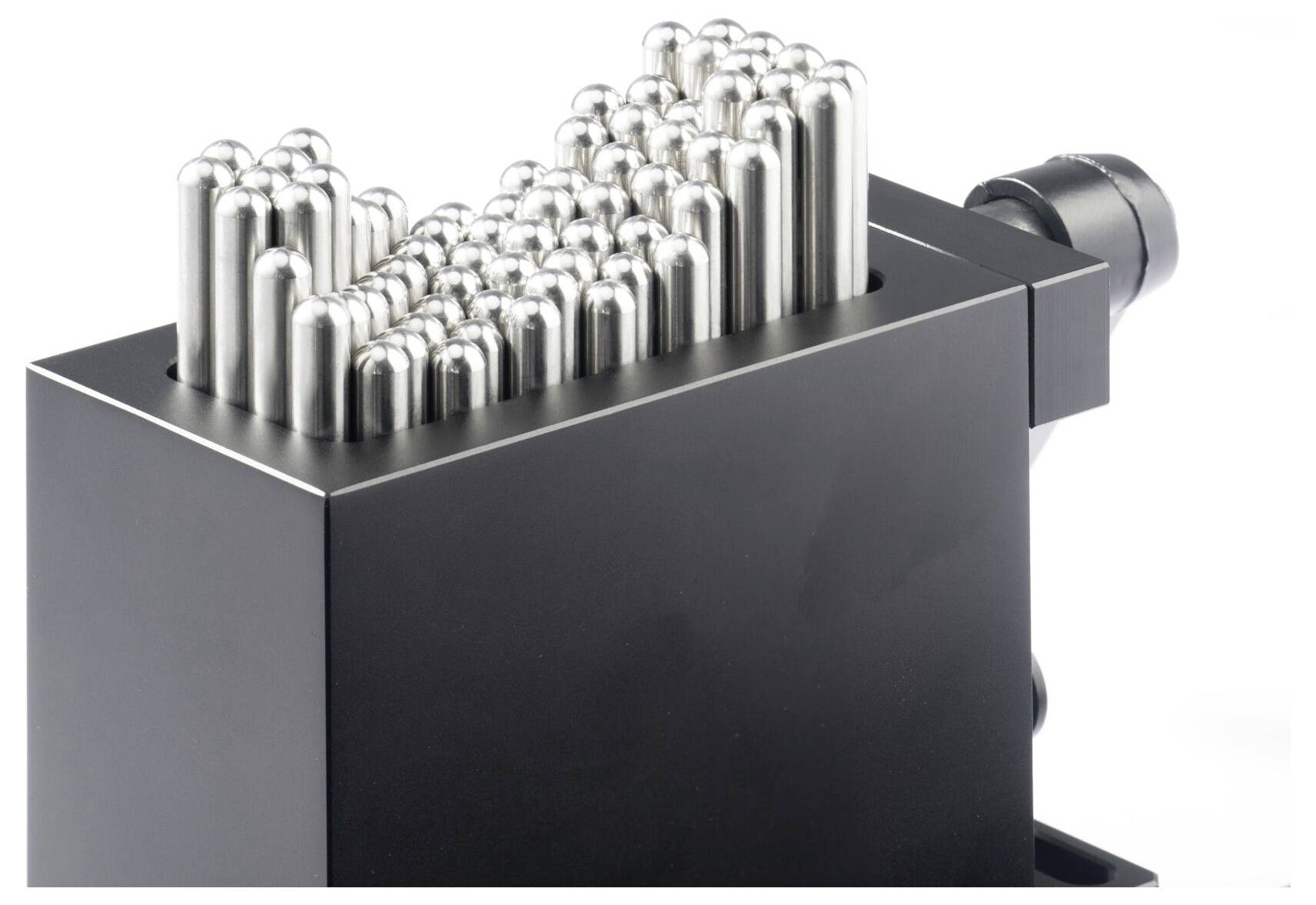 Czarne urządzenie metalowe z rzędami błyszczących cylindrycznych szpilek lub elektrod wyrastających z górnej części, shown na białym tle.