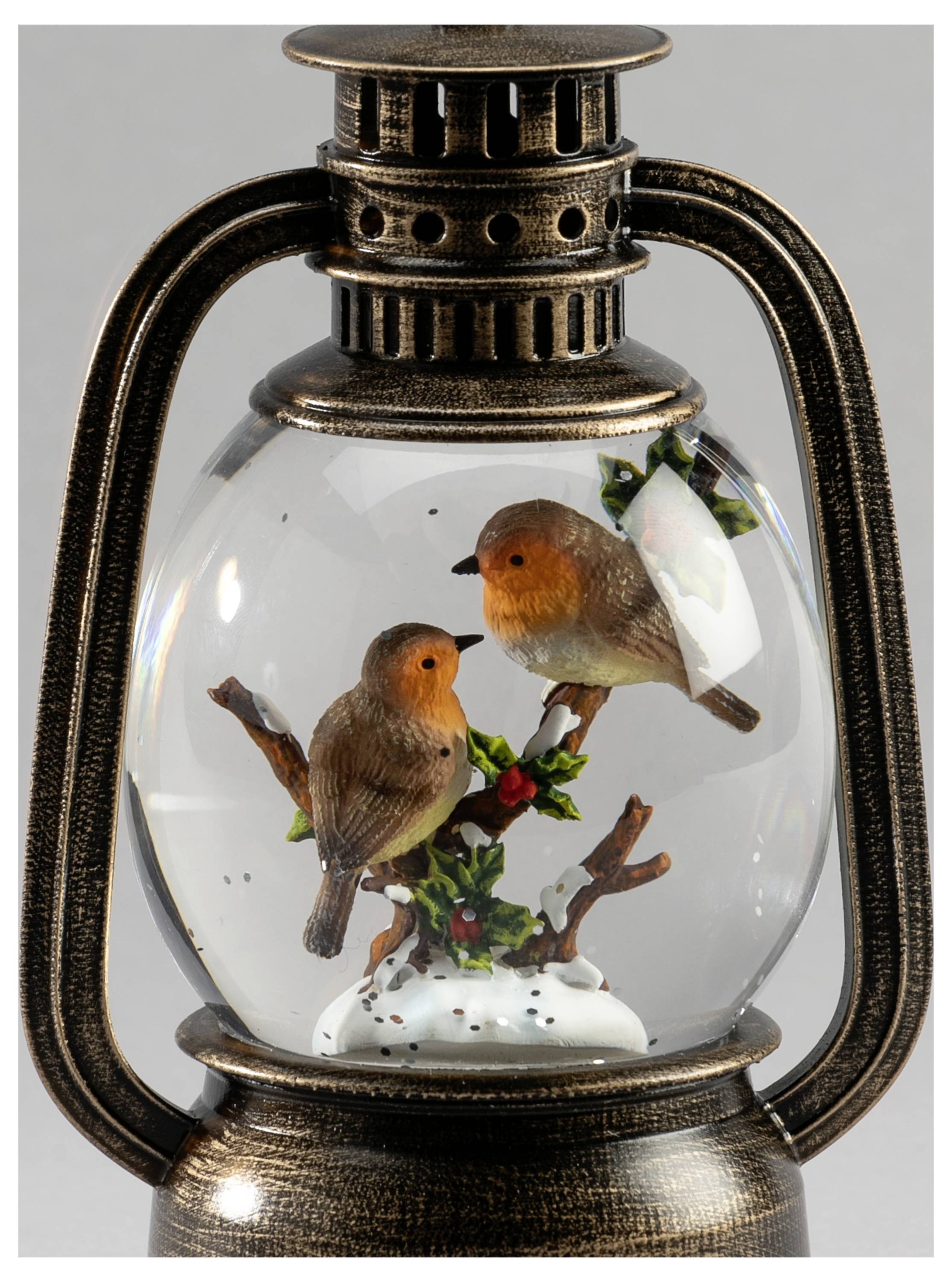 Vintage'owa latarnia ze szklanym globem zawierającym dwa małe ptaki siedzące na gałęziach, tworząc dekoracyjny ornament z ptakami.