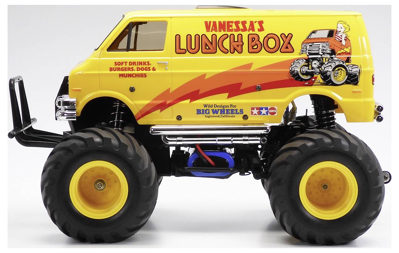 Żółty niestandardowy monster truck food truck oznakowany „Vanessa's Lunch Box" z prześwietlonymi oponami i grafiką tematyczną związaną z jedzeniem.