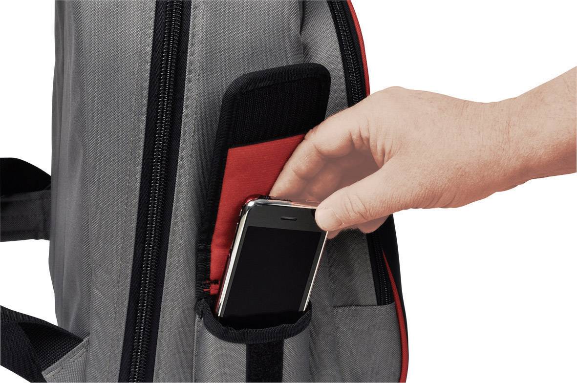 Ręka wkłada smartfon do bocznej kieszeni szarego plecaka.