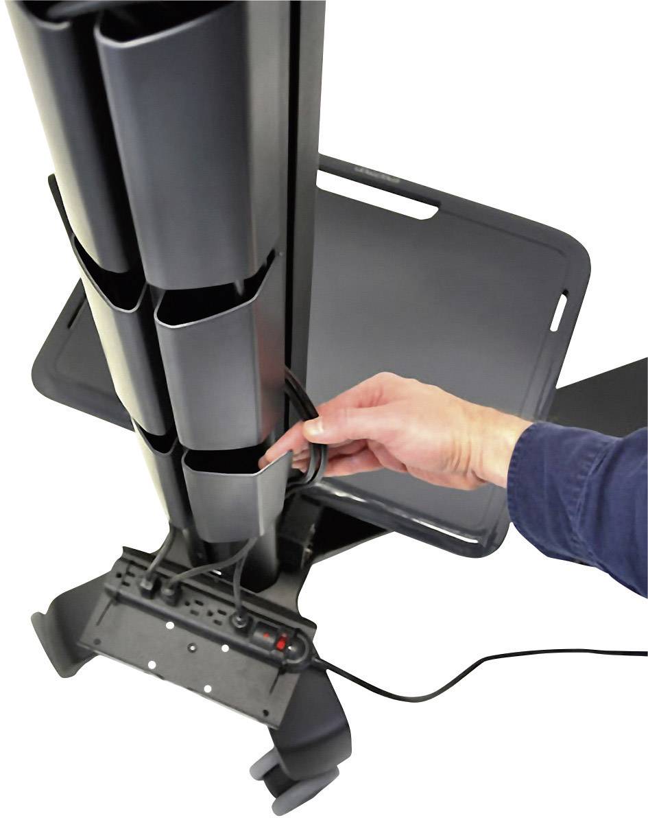 Dłoń osoby wkłada przewód do pionowego, czarnego systemu zarządzania kablami przy biurku.