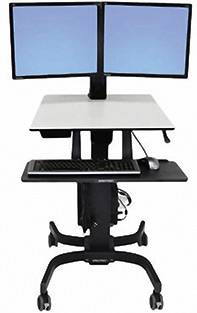Regulowany na wysokość stolik na kółkach z dwoma monitorami ustawionymi obok siebie, klawiaturą i myszą umieszczonymi na osobnych półkach.