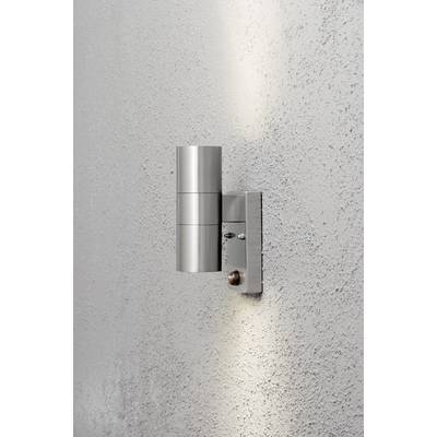 Nowoczesna, cylindryczna lampa ścienna z metalu, która rzuca smugi światła w górę i w dół na jasną, strukturyzowaną ścianę.