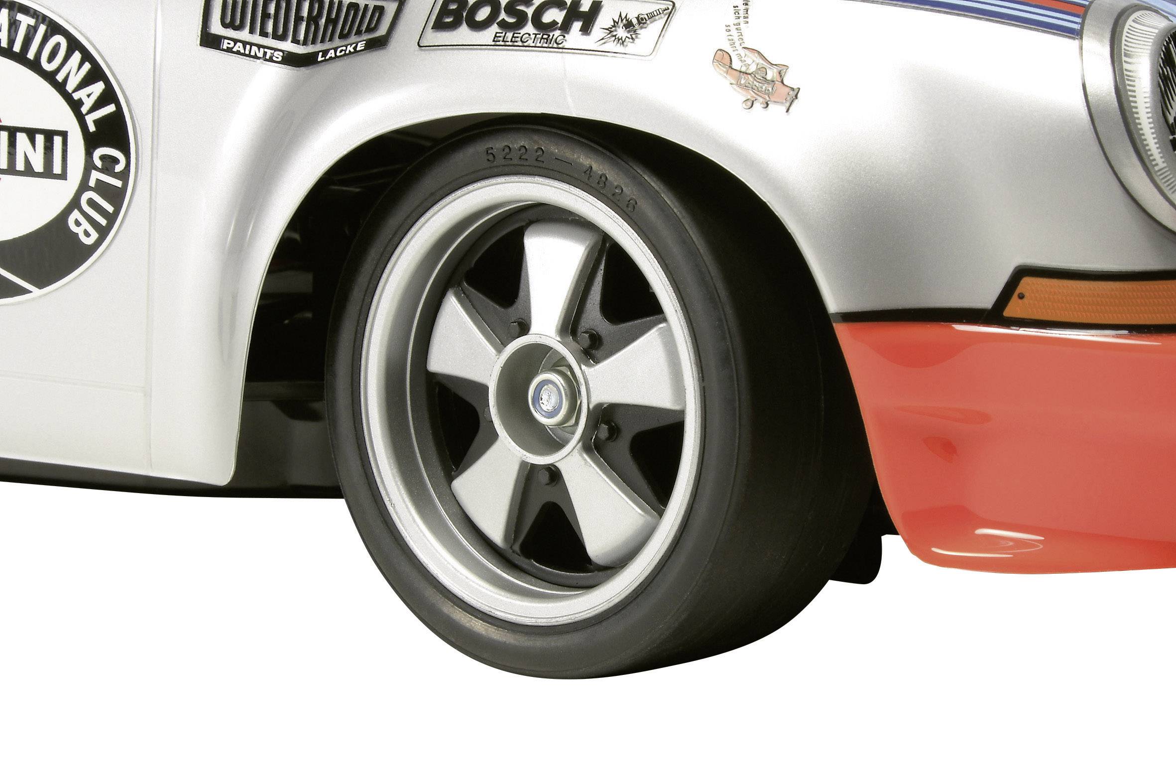 Zbliżenie opony samochodowej z klasycznym wzorem felgi. W lewym górnym rogu widoczne jest logo z napisem 'International Club'.