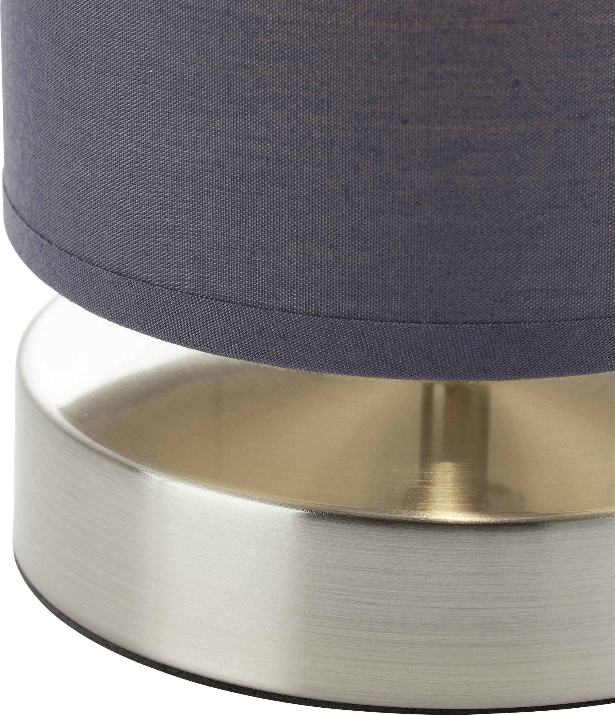 Lampa stołowa z okrągłą, srebrną podstawą i ciemnoniebieskim abażurem z tkaniny.