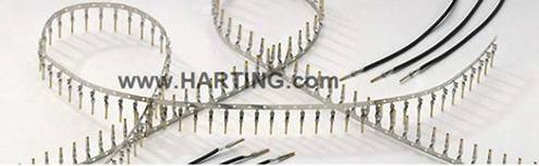 Metalowe piny i kable ułożone są w pętle i równoległe rzędy. Strona internetowa 'www.HARTING.com' jest widoczna pośrodku.