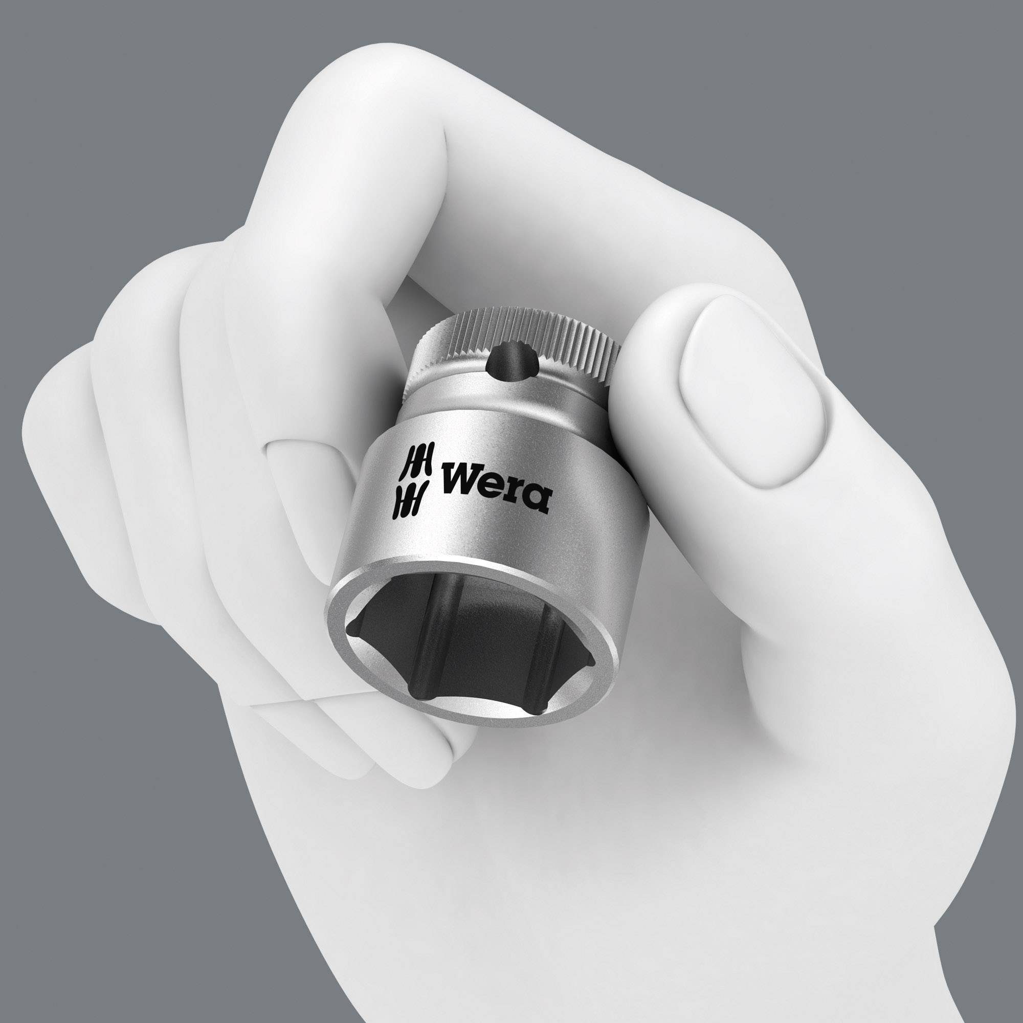 Dłoń trzyma metalowy adapter nasadowy z napisem 'Wera' na szarym tle.