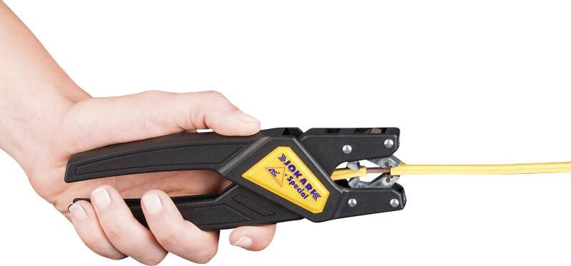 Dłoń trzyma ściągacz do przewodów, który zdejmuje izolację z żółtego kabla. Narzędzie jest czarne z żółtym logo.