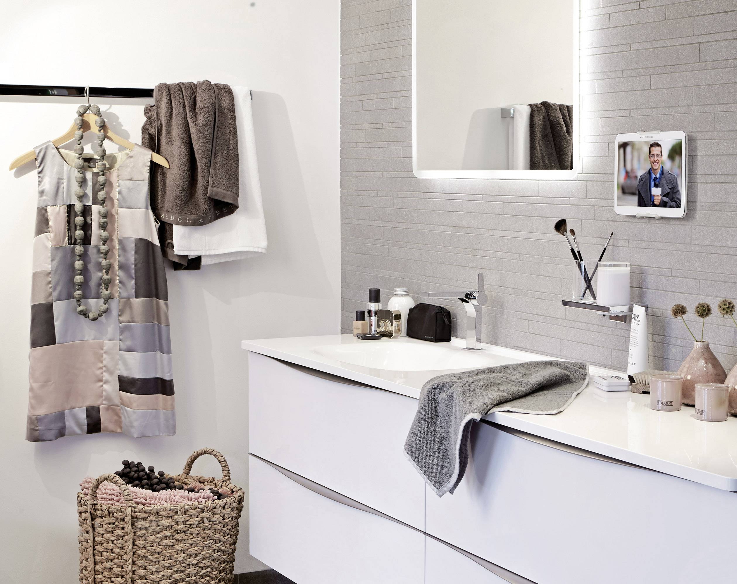 Stylowo urządzona łazienka z nowoczesnym, białym blatem umywalkowym, wiszącą szatą i dekoracyjnym koszykiem.