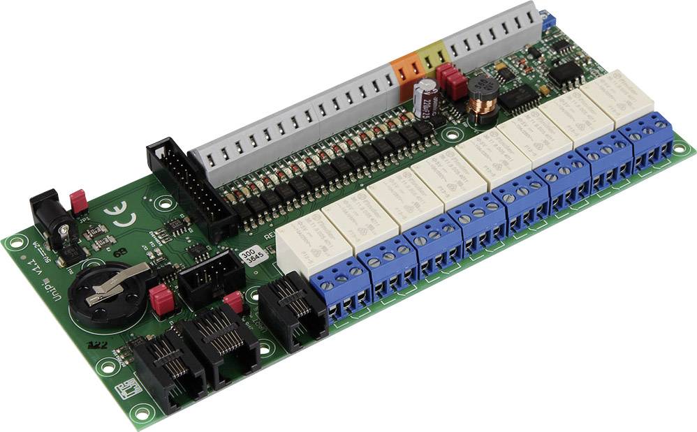 Zielona płytka elektroniczna z różnymi komponentami, w tym niebieskimi złączami, przekaźnikami, czerwonymi przełącznikami i uchwytem na baterię.